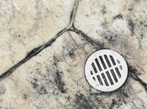 Wet outdoor tile floor drain hole close up